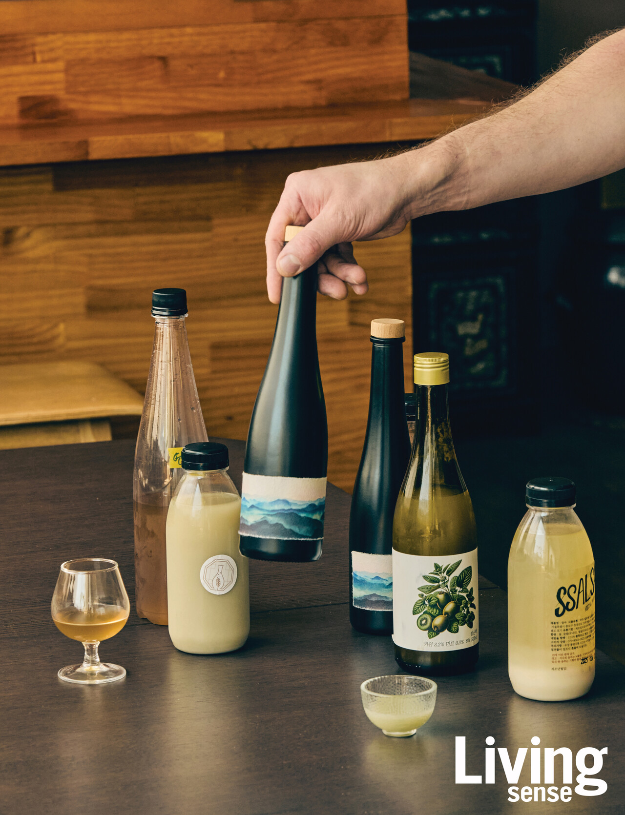 조셉 리저우드 셰프가 들고 있는 산초 막걸리. 한지 라벨 위에는 산의 능선을 담은 이미지를 인쇄했다. 그 옆에는 더술컴퍼니가 만든 연엽주와 막걸리 ‘쌀싸’, 키위와 민트가 들어간 막걸리 ‘밤산책’도 함께 놓여 있다.
