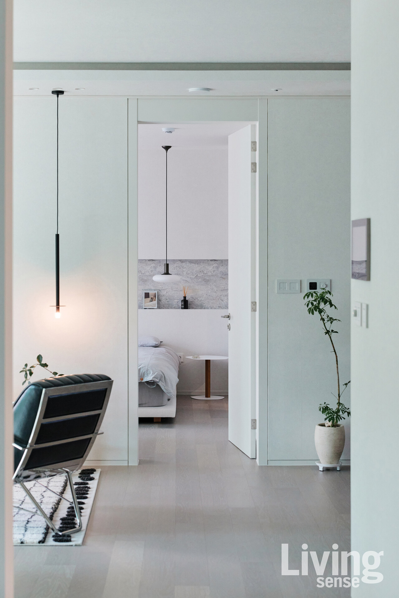 프레임처럼 열린 문 너머 패브릭 벽지가 공간에 은은한 온기를 더하고, 빛과 그림자가 차분히 스며든다. 디자이너가 가장 아름답다고 말한 이 집의 시선.