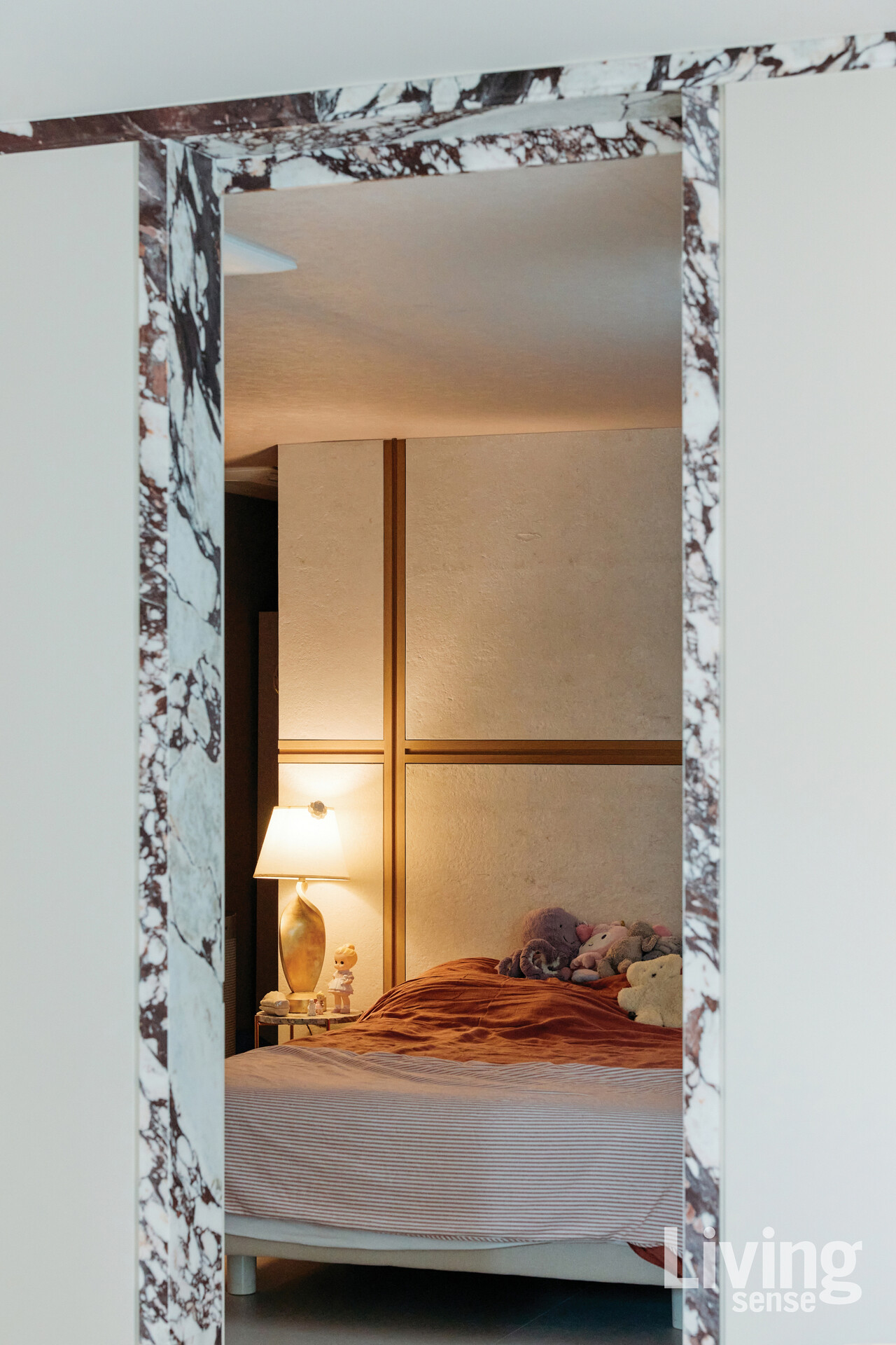 대리석의 차갑고 단단한 느낌을 순화시켜 주는 따뜻한 색감의 패브릭과 조명으로 꾸민 침실.