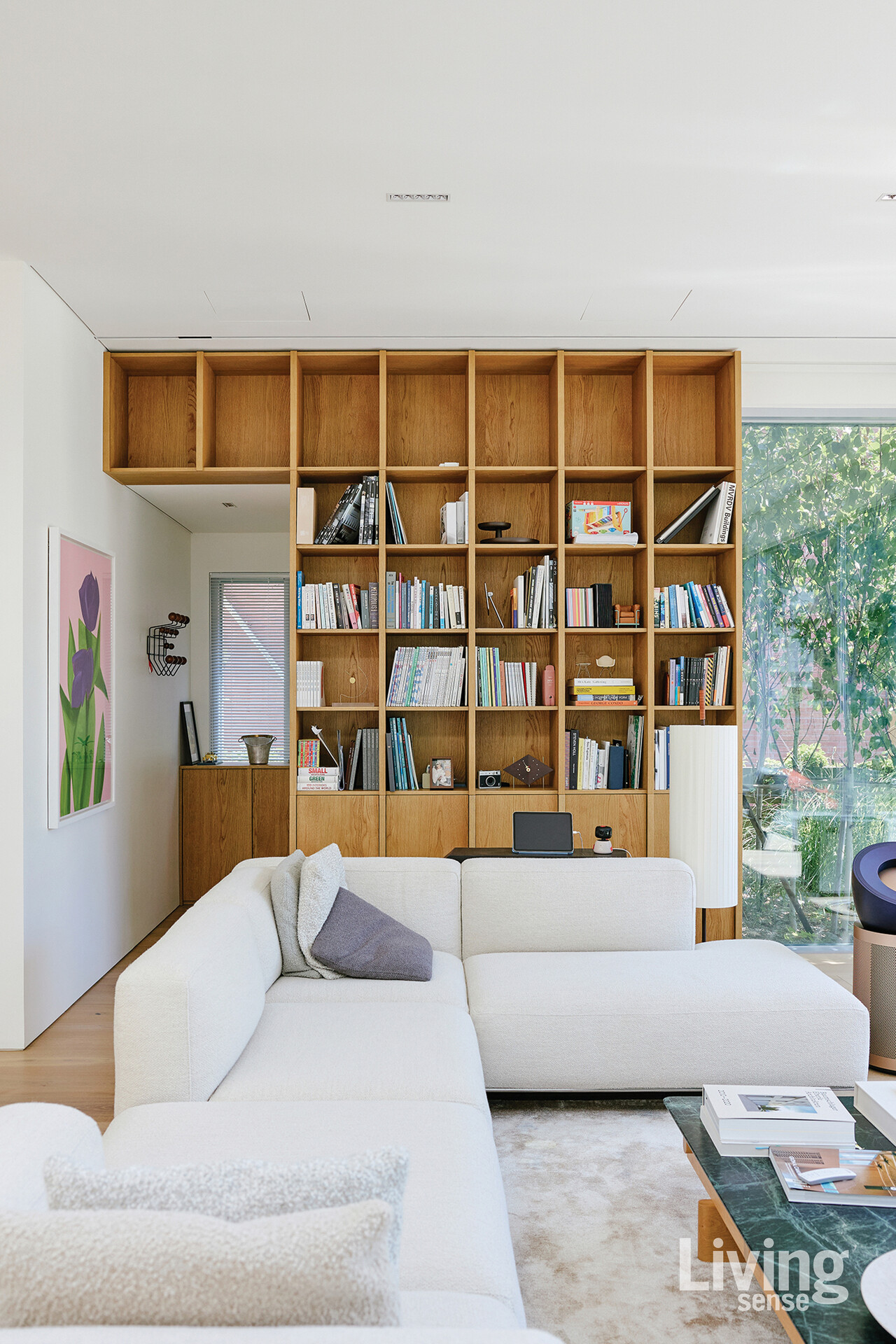 천장까지 높인 맞춤 책장은 수납과 디스플레이, 2가지 역할을 동시에 한다. 기성품으로는 담기 어려운 책의 크기와 오브제를 고려해 제작한 덕분에, 거실은 서재이자 가족의 일상 기록을 품는 공간이 되었다.